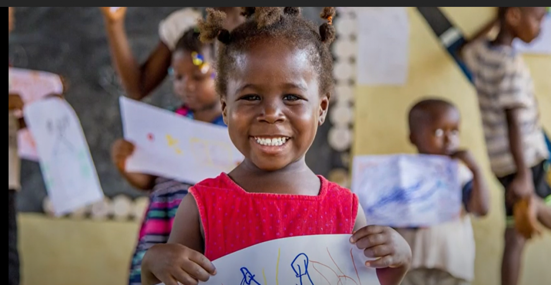 Little girl smiling while holding a painting