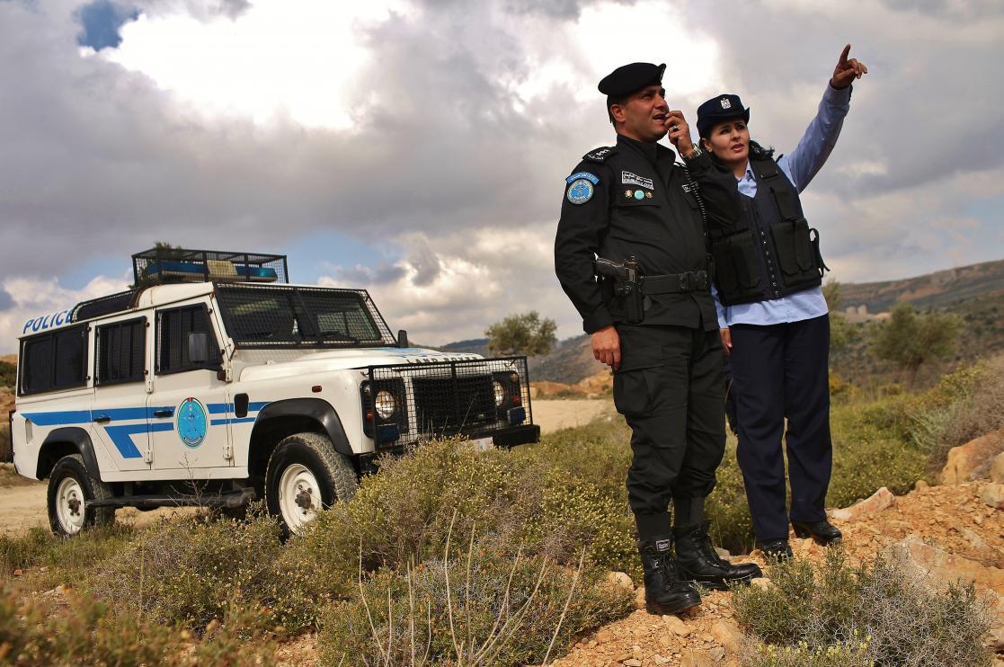 Two police officers in front of the car, one of them pointing and the other talking on the radio