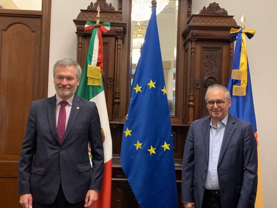 Two men posing with flags in the background