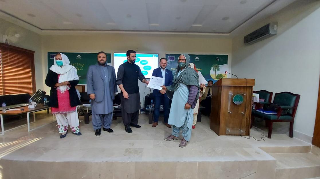 Group of people posing while two men holding a document