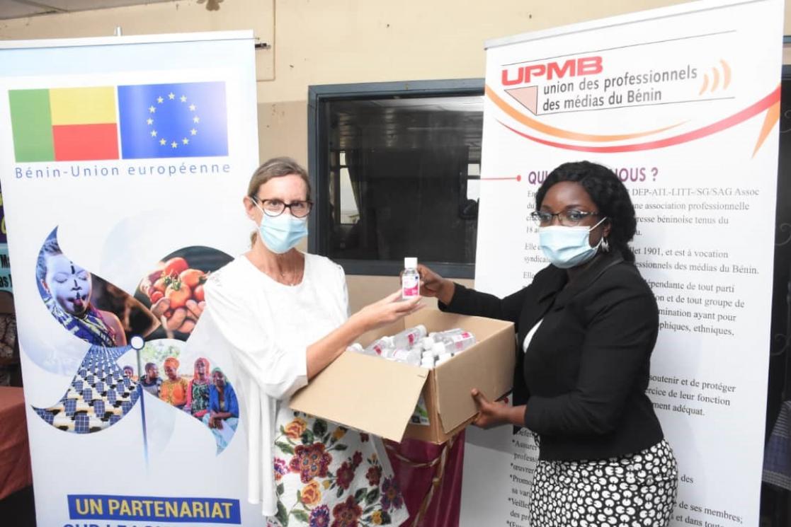 Two women posing holding a small bottle and a box filled with more small bottles