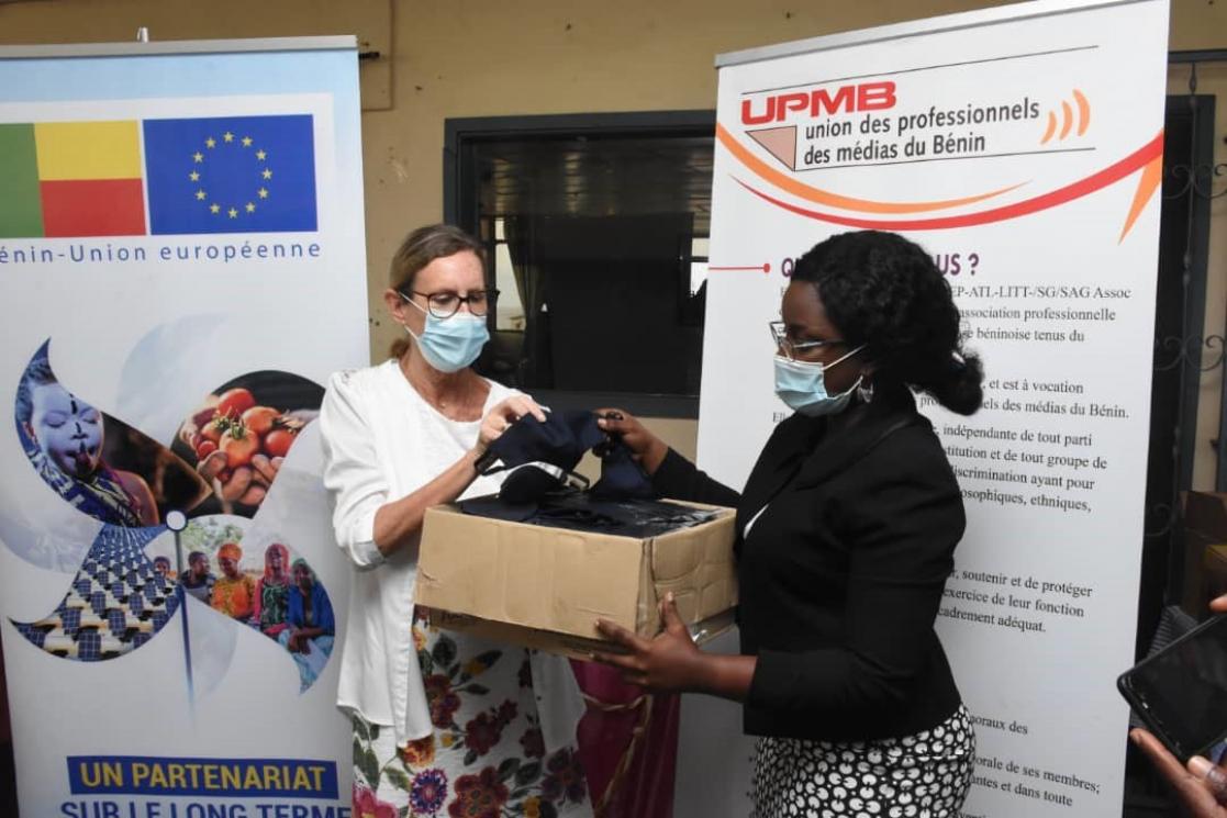 Two women posing holding a box filled with sanitary masks