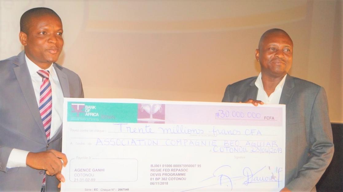 Two men posing holding a cheque