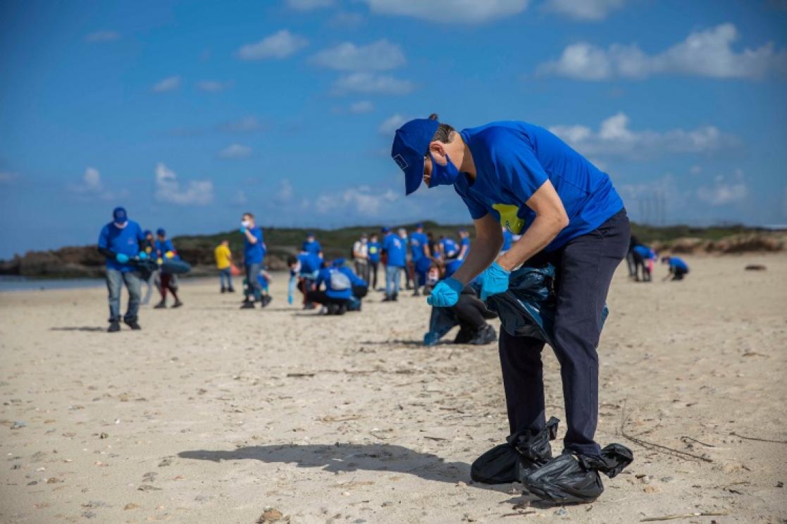 group of people cleaning a beach 