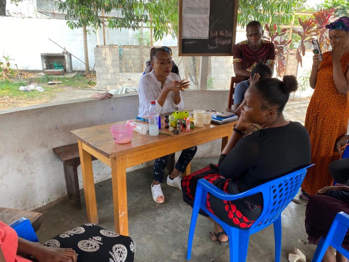 Two women talking while sitting at a table with people around them