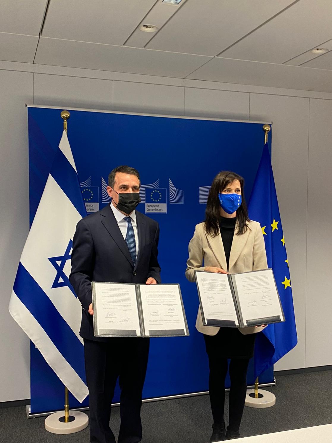 Two people posing at a photocall showing two documents