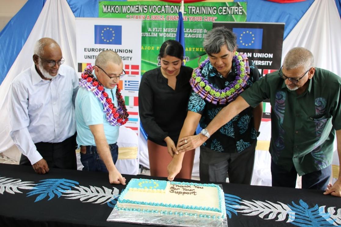 Four men and a woman cutting a cake