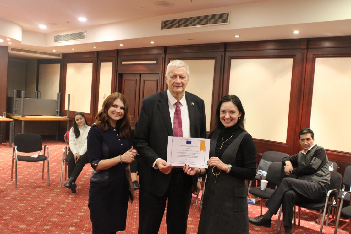 Two women and one man posing holding a diploma