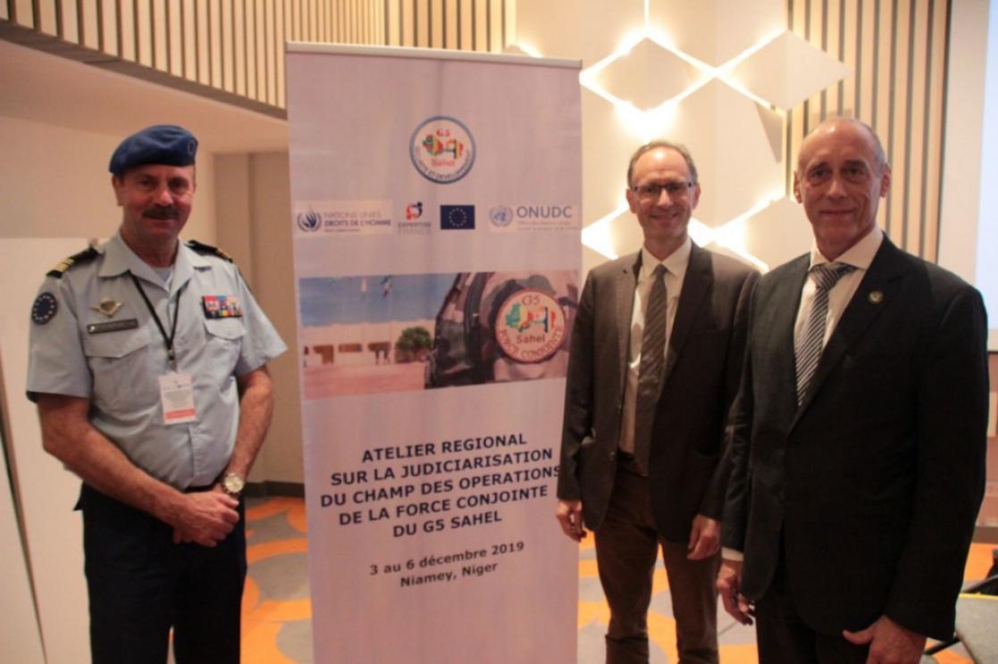 three men in front of a conference poster 