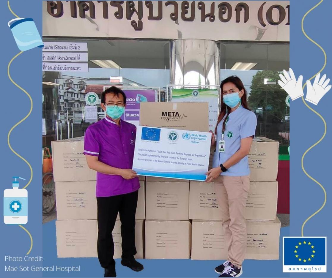 Man and woman posing in front of boxes holding a poster