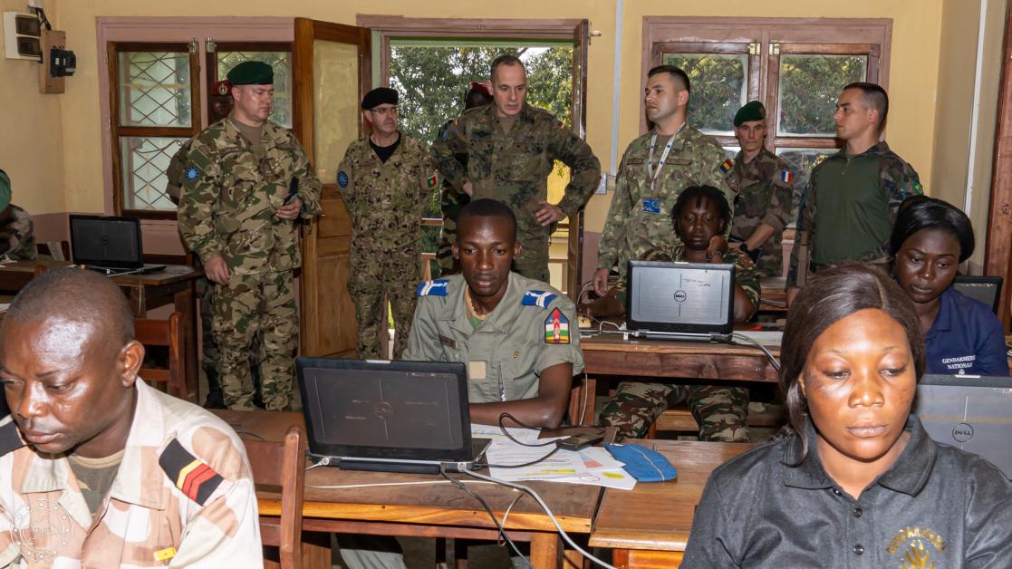 People standing and sitting in front of a computer