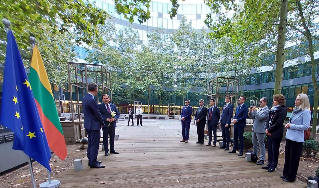 A group of 12 people assemble at memorial site. 