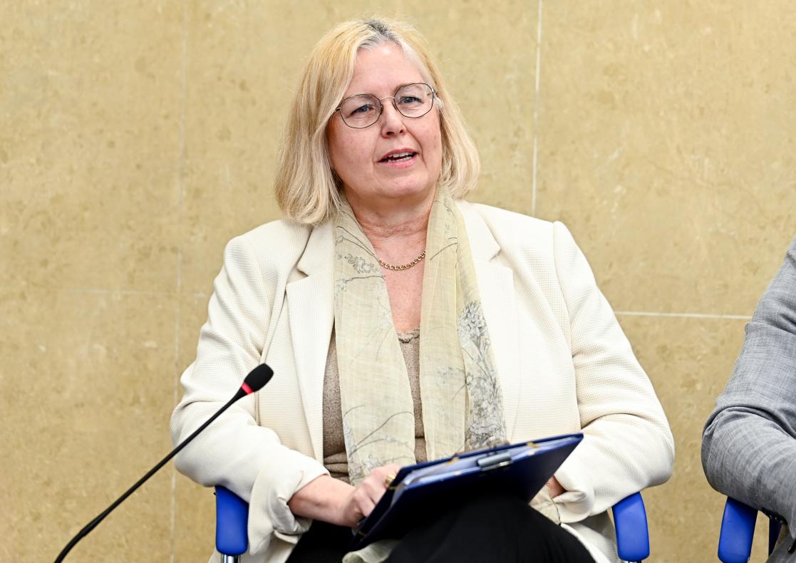 Liselotte Isaksson sitting and speaking in front of a mic.