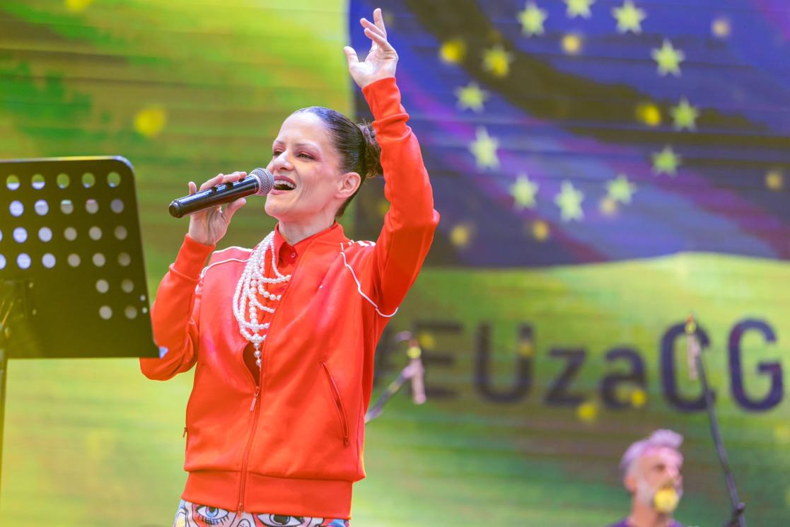 Singer Marija Božović on stage. Behind her is the EU flag and sign EUzaCG