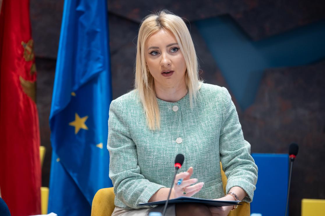 Minister of European Affairs Maida Gorčević sitting by the Montenegrin and EU flag
