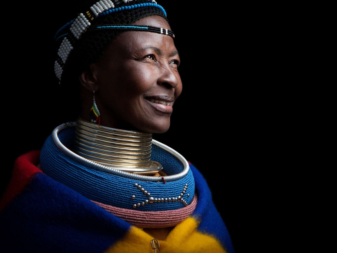 Mature African lady in tribal ceremonial costume smiling. 