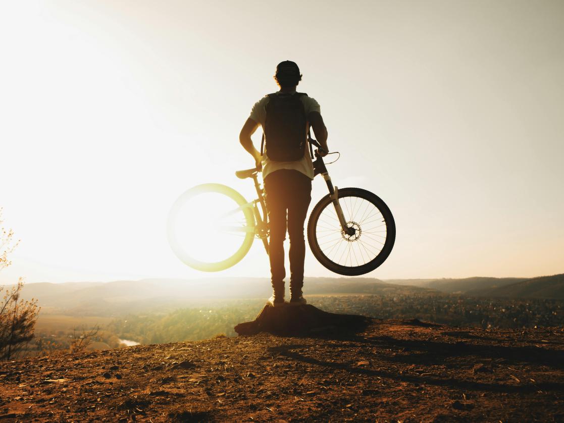 Silhouette of a person holding a bike 