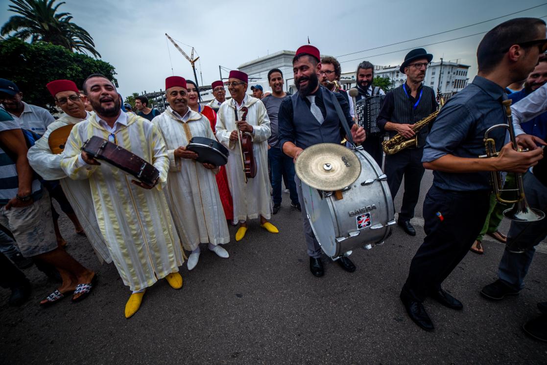des musciens en habit tradictionnel marocain aux côtés de musiciens de jazz dans la rue