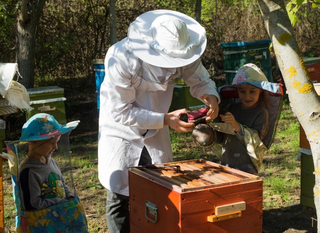beekeeper with children helping