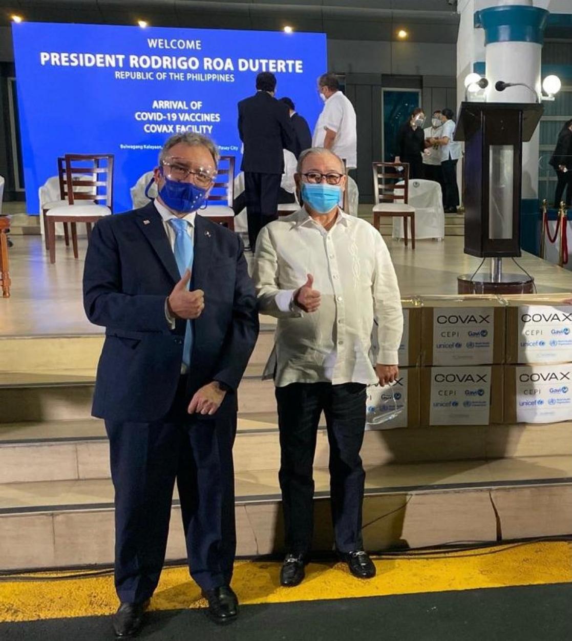 Two men with COVAX boxes