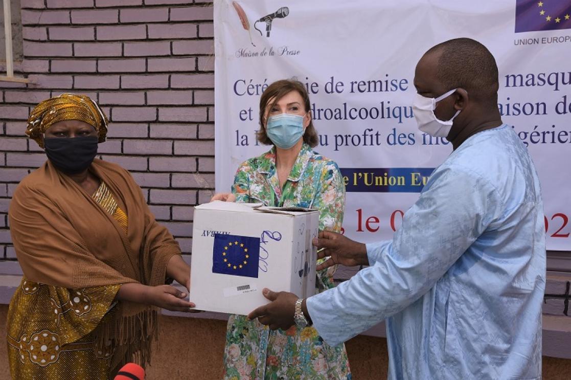 Two women and a man posing holding a box
