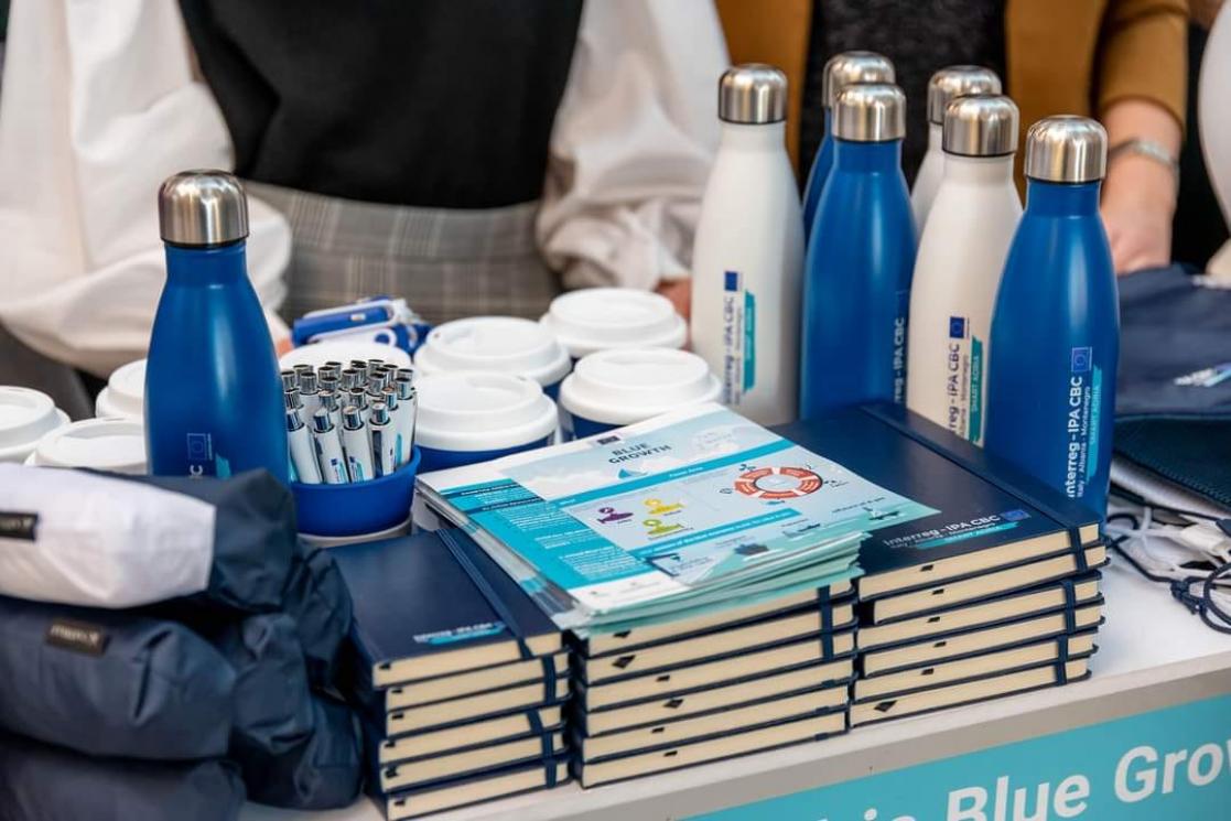 White and blue merchandising pens, notebooks, mugs and bottles