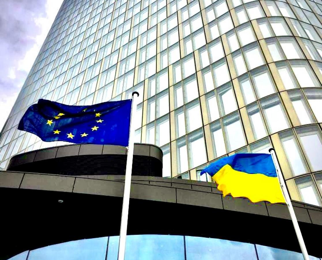 Two flags of Ukraine and the EU in front of a building