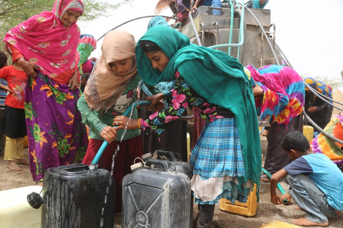 Group of children and woman with a estructure of drinking water