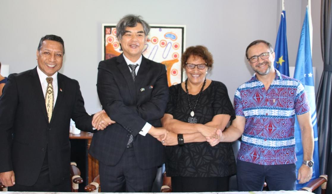 Three men and a woman posing with their hands shaking