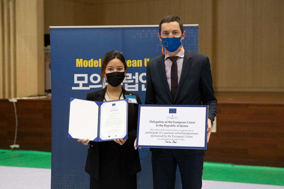 Man and woman posing, the woman with a diploma