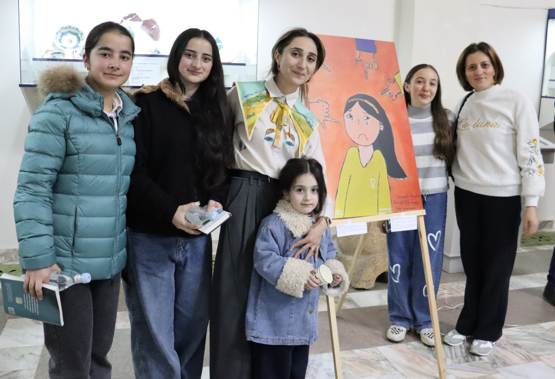 Artist posing in front of her picture with the whole family.