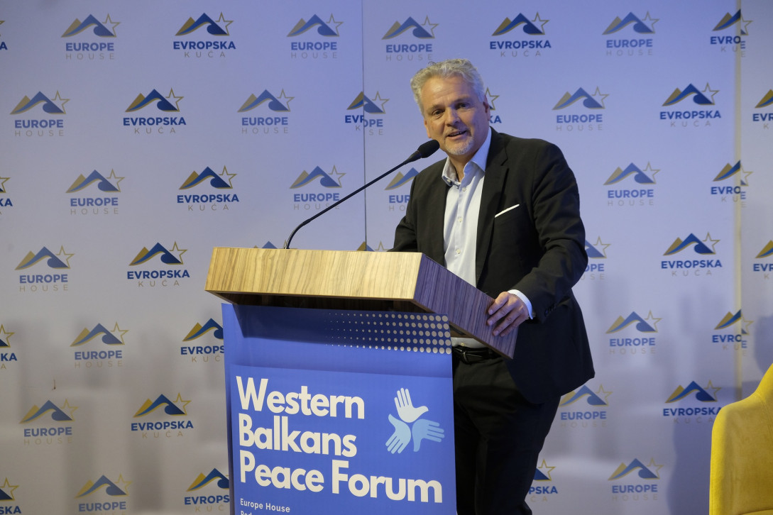 Ambassador Sattler standing behind lectern and speaking