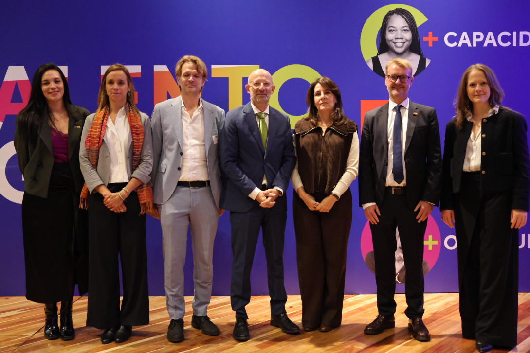 Personas asistentes al evento de pie sobre el escenario