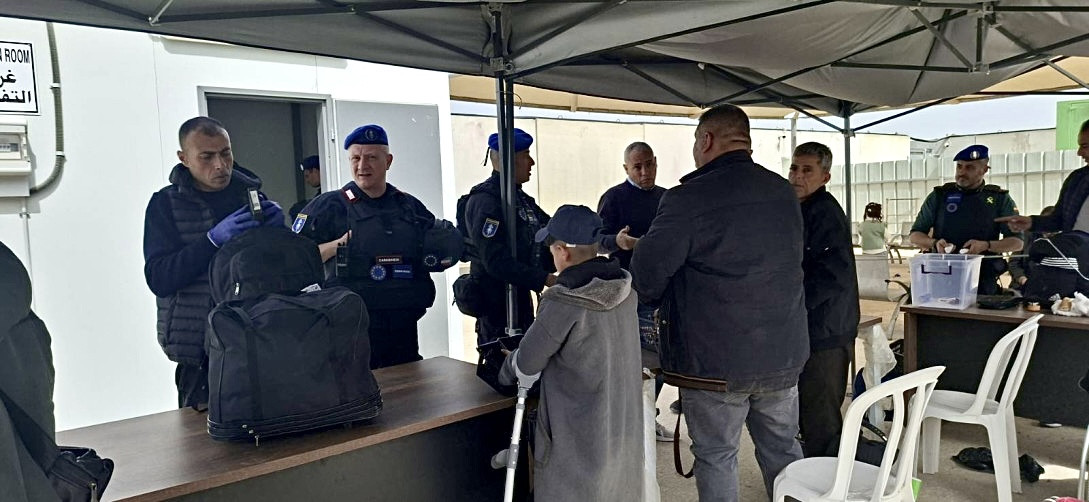 EU personnel monitoring passenger processing at a covered checkpoint area.