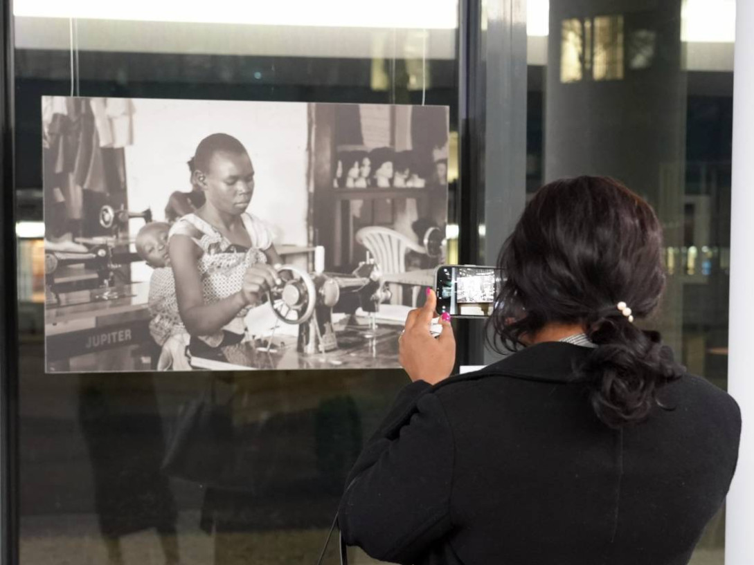 Behind the scenes photo of a woman taking a snapshot of an art exhibition. 