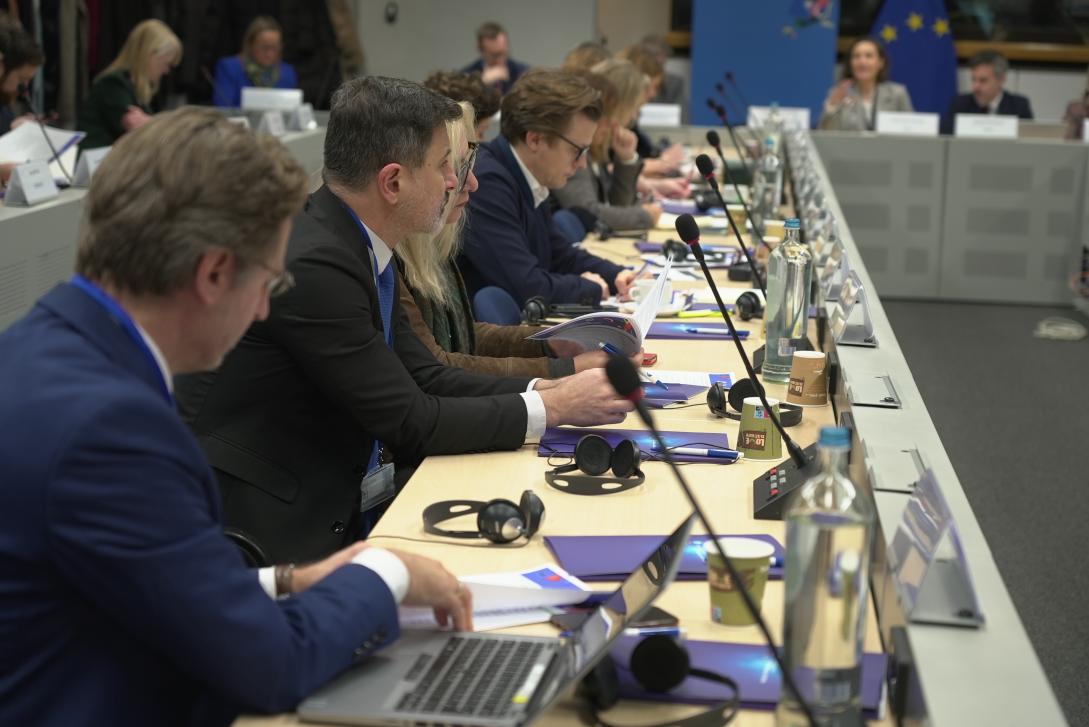 Picture of participants of the EU Communication Directors' Meeting, where a row of participant is seen sitting at a table, whilst listening to a speaker in the background