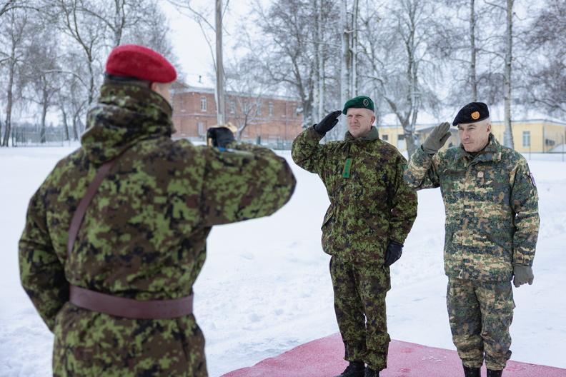Two senior soldiers salute soldier with back to us, snowy day. 