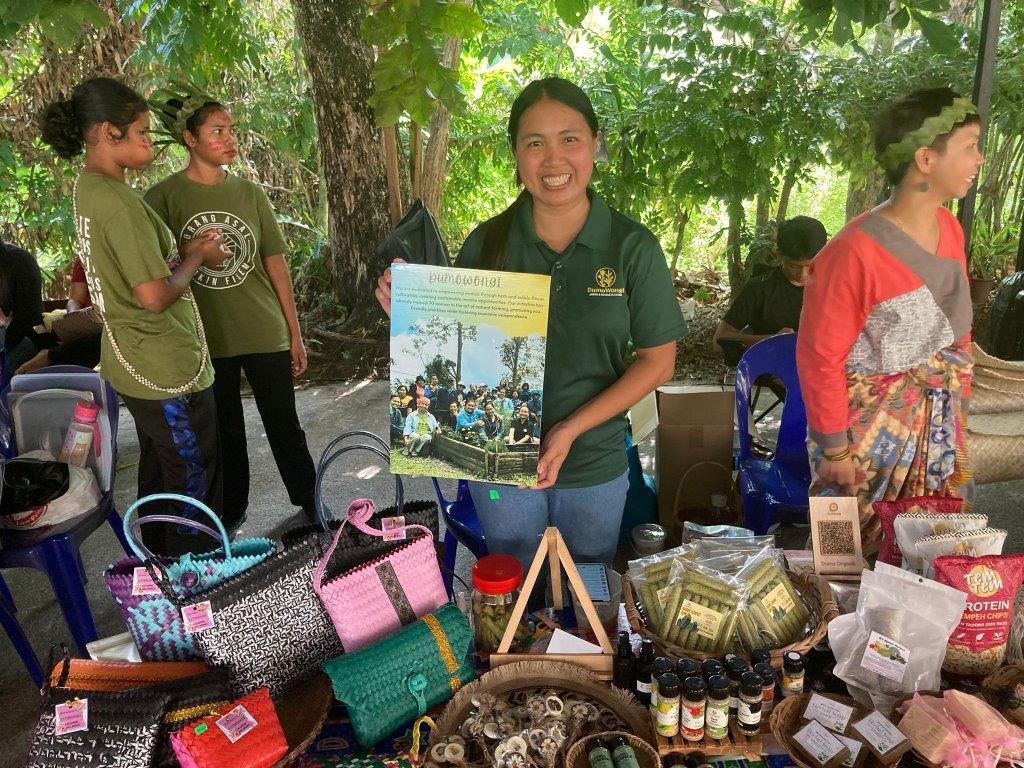 A woman from Sabah showing her handcraft with a placard in her hand.