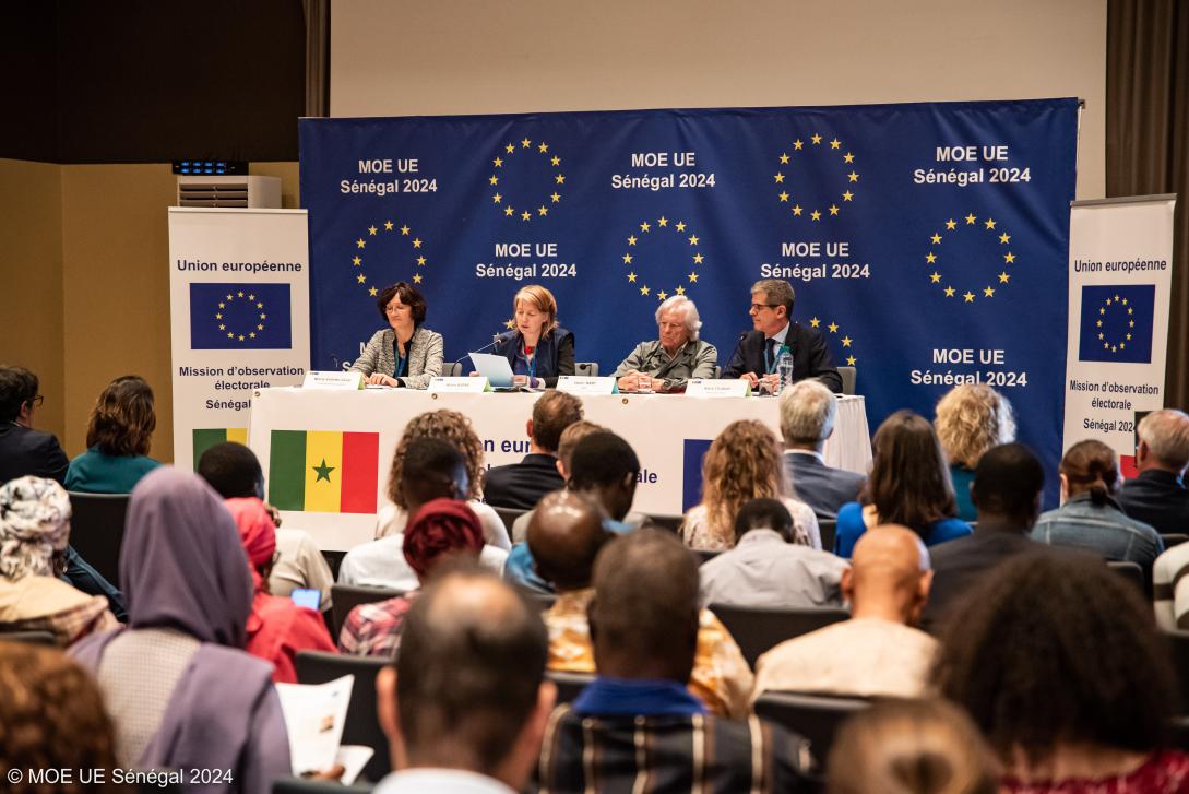People at a press conference with EU branding in background