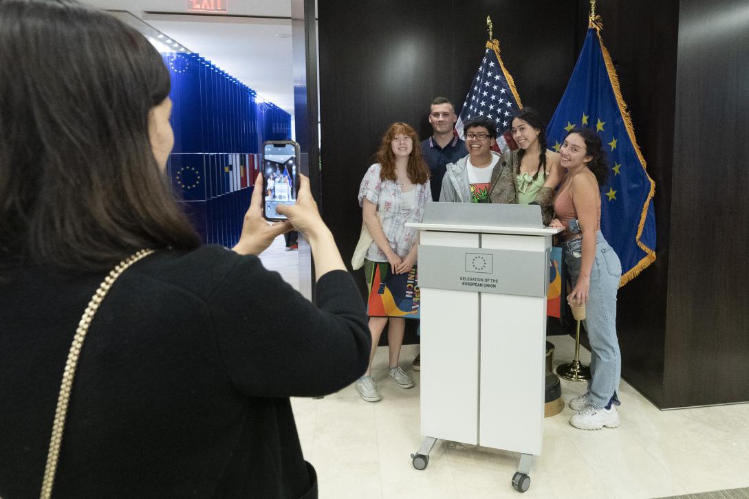 A person takes a picture of a group of friends behind a podium at EU Open House