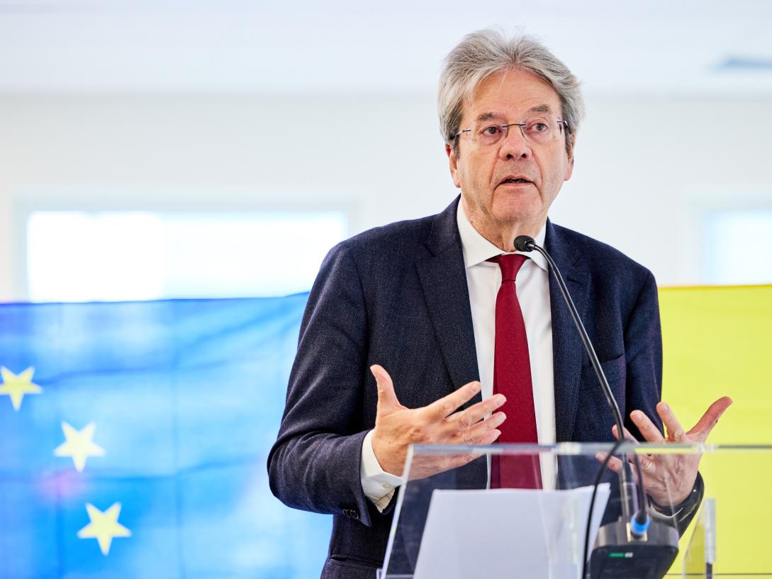 Commissioner Gentiloni speaking at a podium.