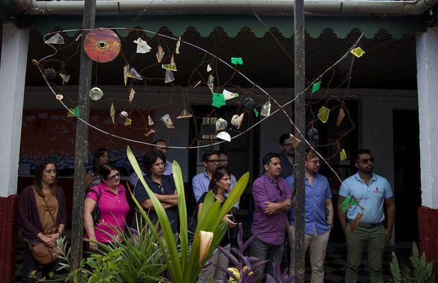 Group of people standing under the roof of a patio with a sculpture.