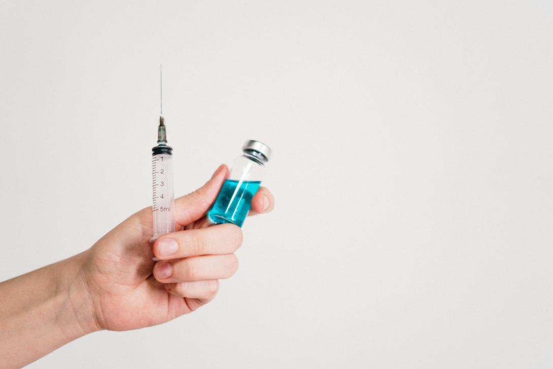 Hand Holding Syringe and Vaccine Bottle