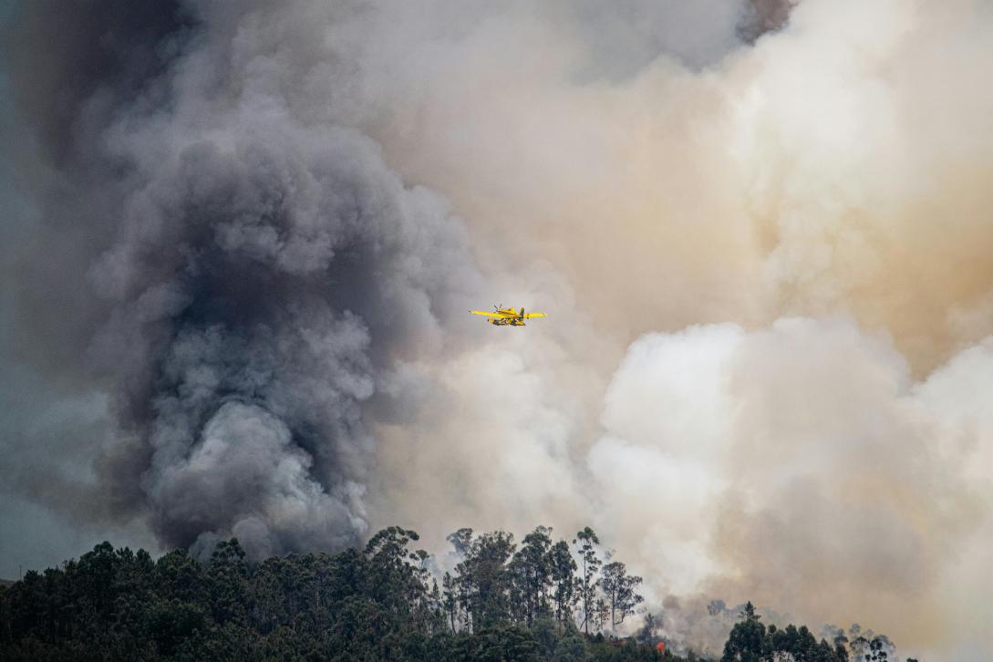 firefighting plane in the air above forest fire smoke