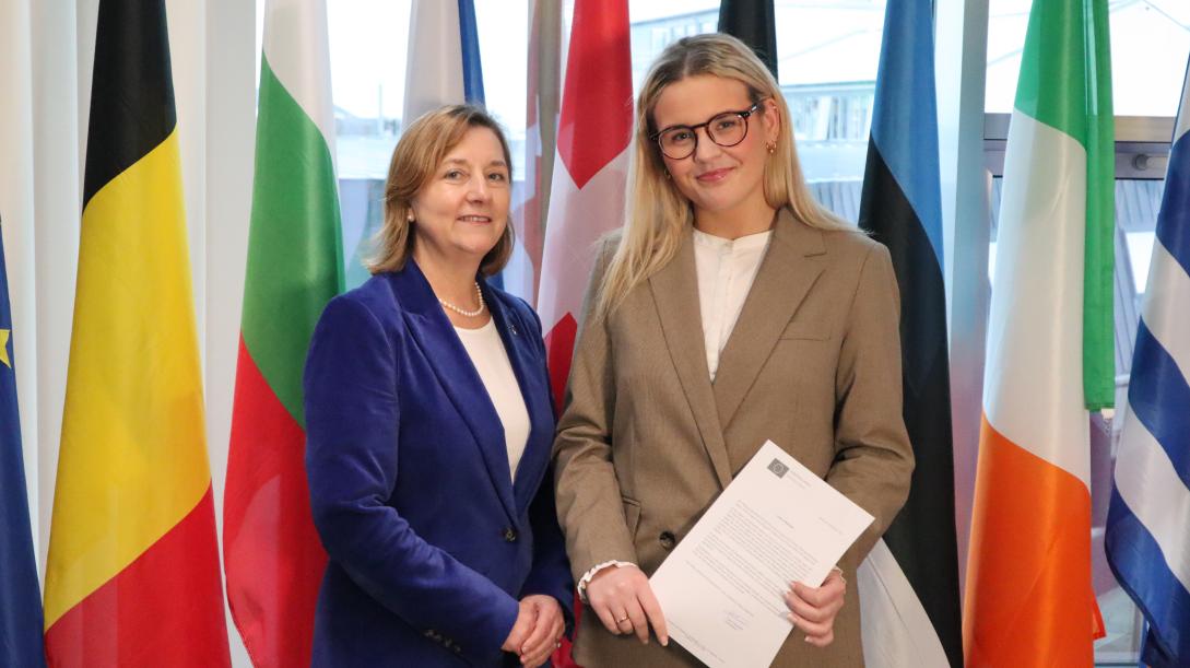 picture of two women. Multiple colourful European flags in the background.