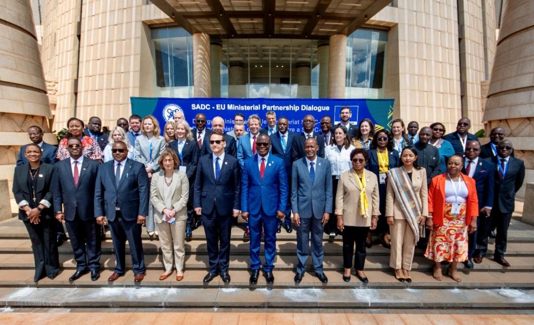 A group photo of delegates to a conference on the steps of a grand building.