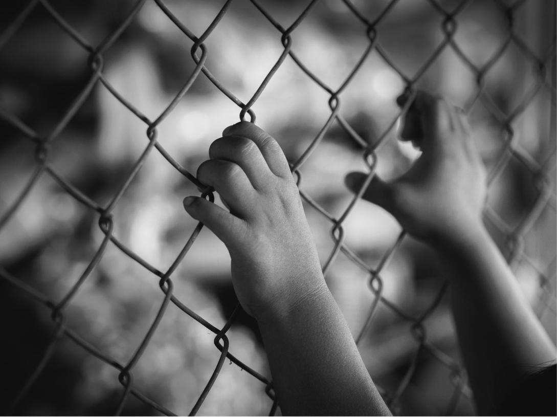 Hands holding fence