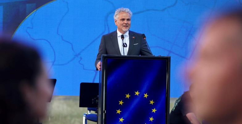 Ambassador Sattler standing behind lectern and speaking