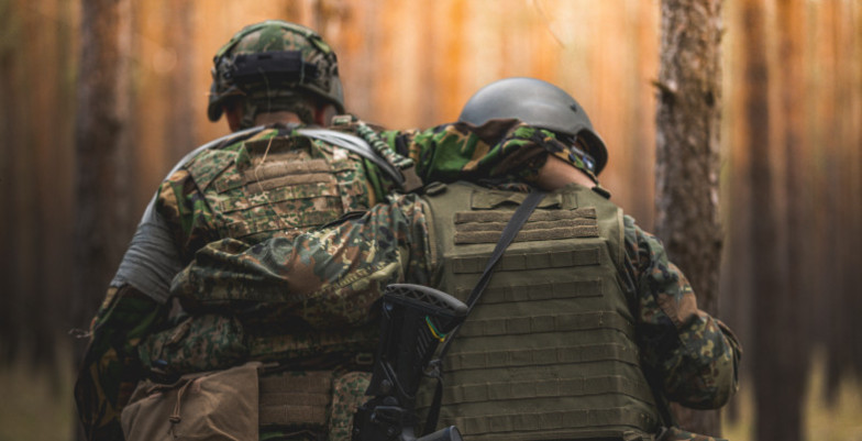 Two Ukrainian soldiers support one another during a training exercise.