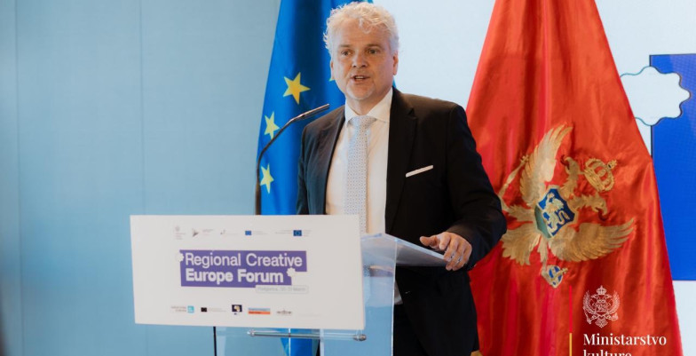 Ambassador Sattler standing behind lectern and speaking